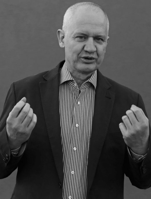 Senior businessman in suit jacket making a gesture, in black and white.